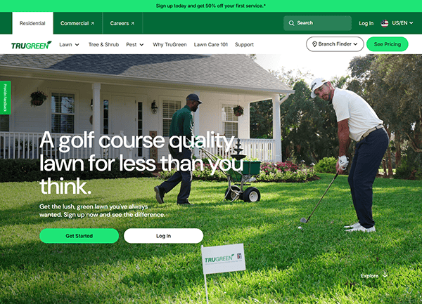 Two men are on a well-maintained lawn; one adjusts a flag while the other mows. A white house and trees frame the scene. TruGreen marketing text graces the left, making it perfect for local service company websites seeking to showcase their commitment to pristine landscapes.