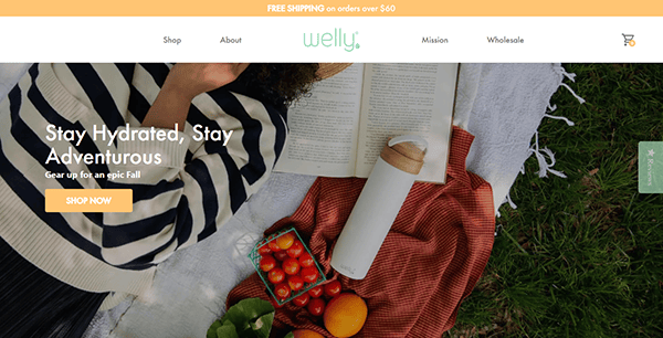 A person reads a book on a picnic blanket with a water bottle, cherry tomatoes, an apple, and a basket nearby. Text overlay promotes hydration, fall adventure, and highlights the inspiration found in the best small business websites.