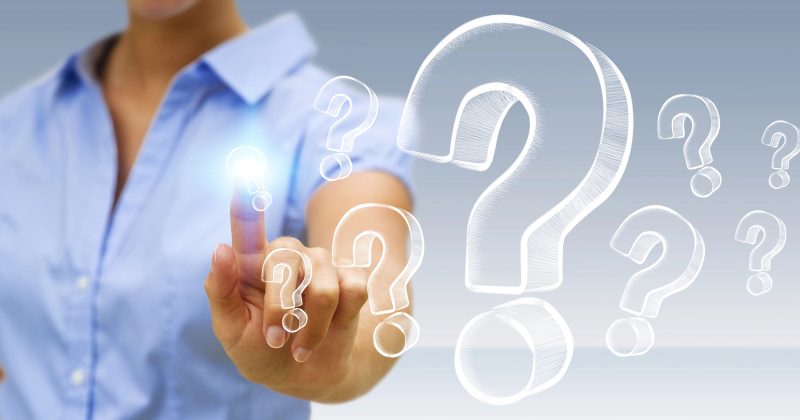 A person wearing a blue shirt touches a virtual screen displaying large, translucent question marks.