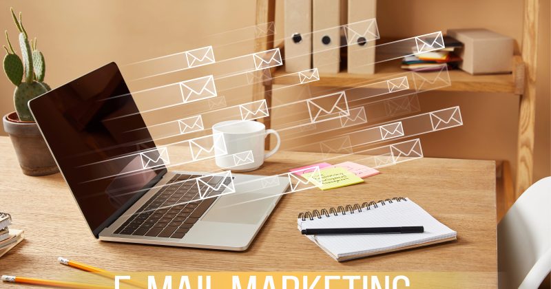 A laptop on a desk with illustrated email icons and office supplies, highlighting the concept of email marketing.