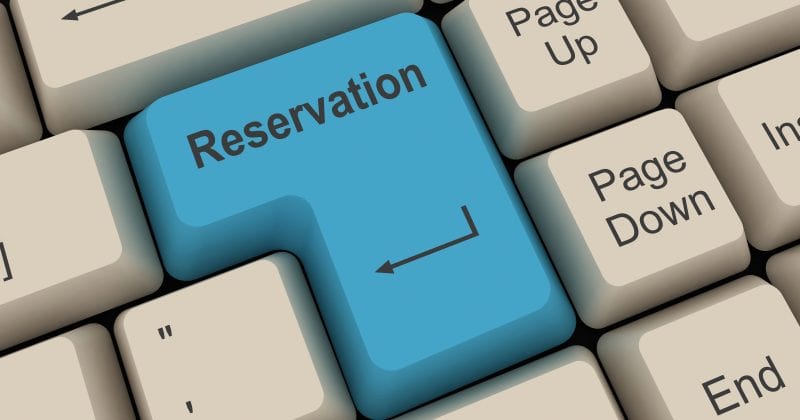 A computer keyboard features a large blue key labeled "Reservations" replacing the Enter key. Surrounding keys include Backspace, Page Up, Page Down, and Shift. Perfect for showcasing the ease of online bookings or a WordPress Hotel Booking Plugin.