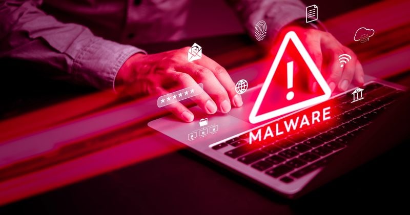 Person typing on a laptop with a glowing red "Malware" warning symbol and various digital icons, indicating a cybersecurity threat.