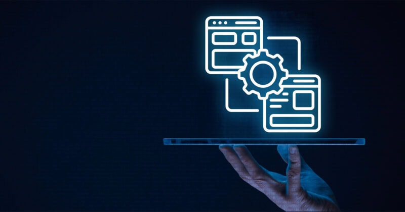 A hand holds a flat transparent surface displaying glowing digital icons of web pages and a gear, symbolizing technology and web development.