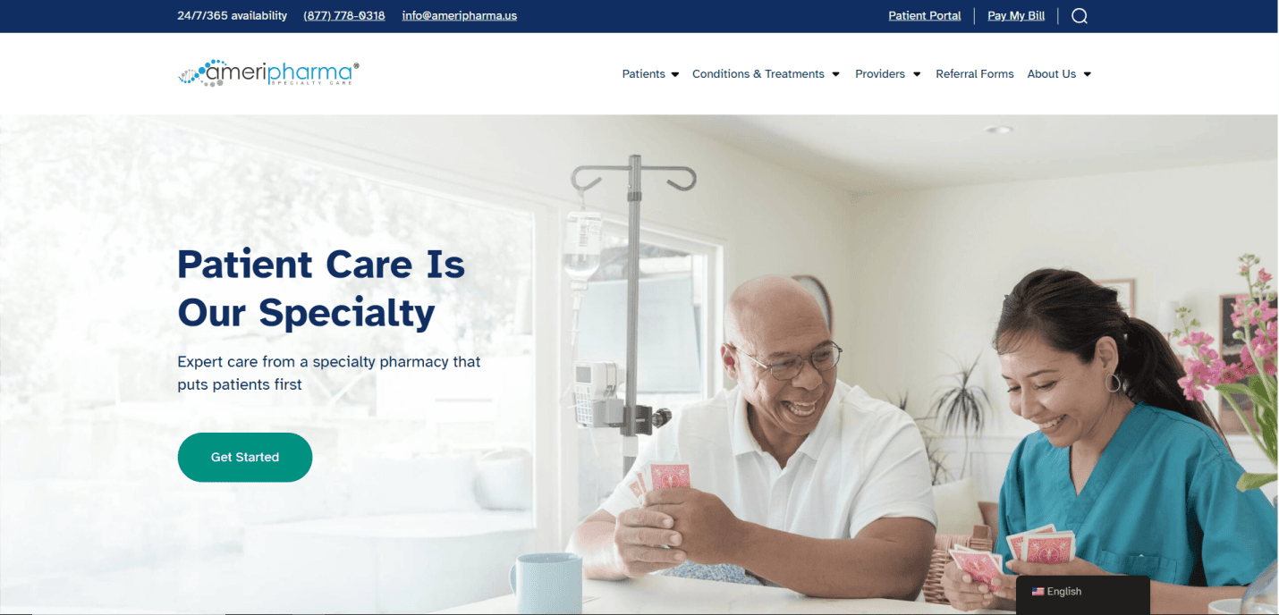 A smiling healthcare worker sits at a table playing cards with an older male patient in a bright room; an IV stand is beside them. The screen displays the AmeriPharma logo and “Patient Care Is Our Specialty”—perfect inspiration for manufacturing website design.