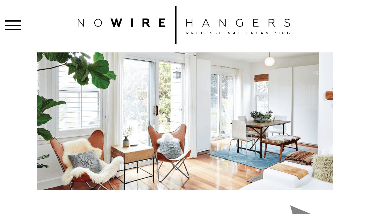 A bright, modern living and dining area with large windows, wooden floors, white walls, lush plants, cozy chairs with fur throws, and a small dining table—perfect for home organizers. Logo reads “No Wire Hangers: Professional Organizing.”.