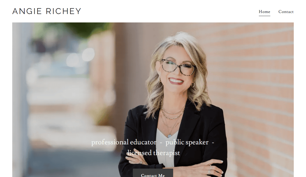 A smiling woman with blonde hair, glasses, and a black blazer stands with folded arms against a brick wall. Text reads: professional educator - public speaker - licensed therapist. Discover therapy services on her therapist website. Menu: Home and Contact.