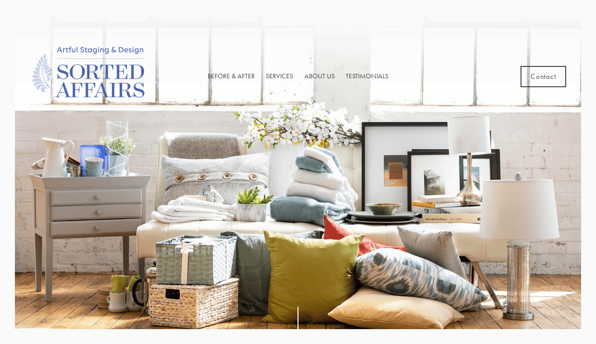 A bright, airy room features a white bench covered with stacked blankets, pillows, towels, and decor items, showcasing a home staging setup perfect for home organizers seeking inspiration.