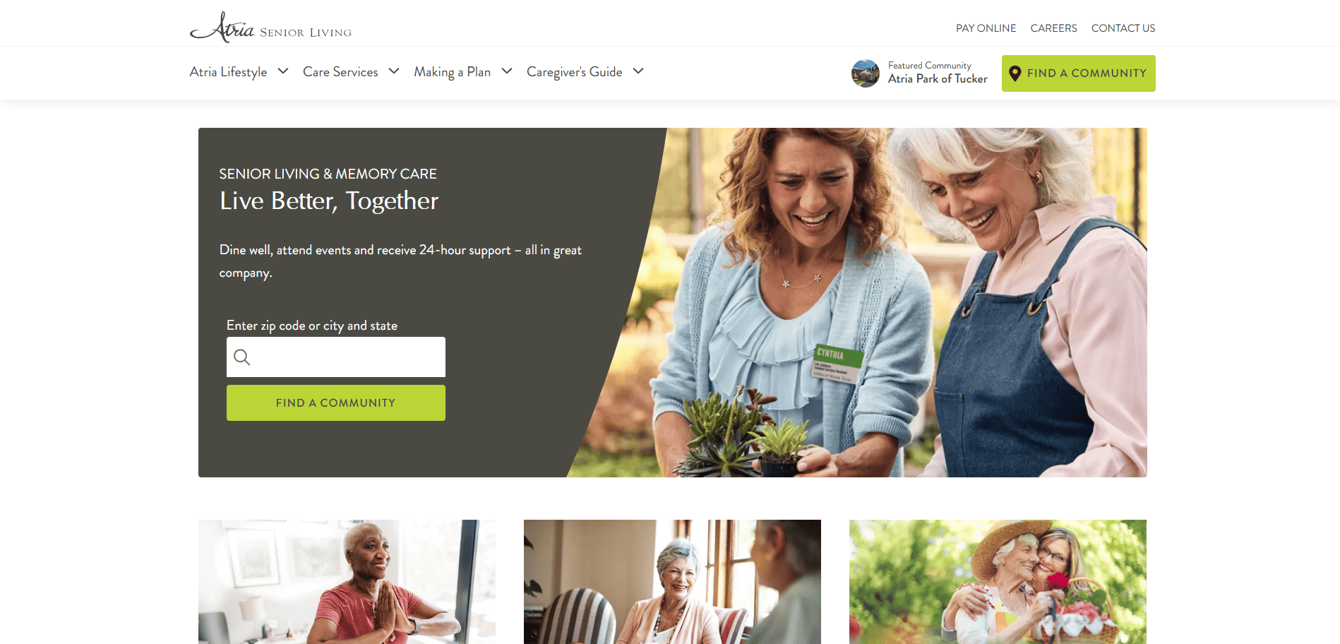 Two older women smile and enjoy gardening together outdoors. One wears a name tag and holds a small plant as the other looks on happily, reflecting the welcoming community featured on this senior living website.