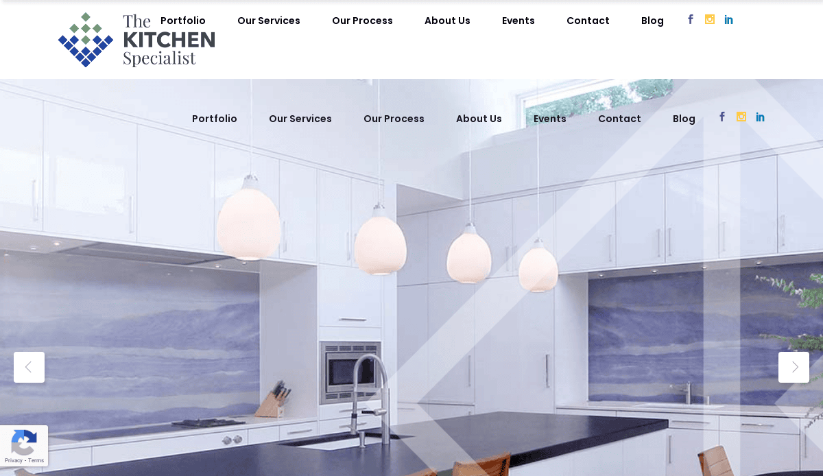 Modern kitchen showroom with white cabinets, blue backsplash, pendant lights, a tall faucet sink, and wooden chairs around a large island under a skylight. Explore our kitchen portfolio using the website navigation bar above.