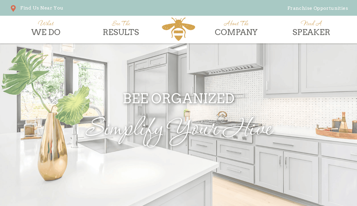 Bright, modern kitchen with white cabinets, a white island countertop, and stainless steel stove. Text on the image reads “Bee Organized: Simplify Your Hive.” Perfect space for home organizers or managing WordPress tasks with ease. Gold vase with green leaves sits on the counter.