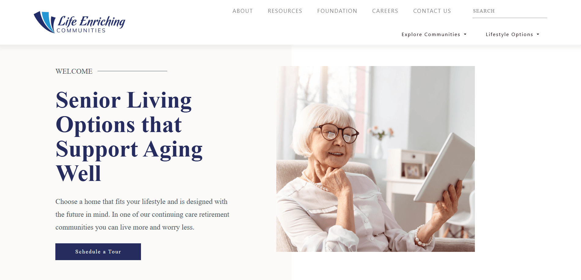 A smiling elderly woman with glasses sits in a bright room, holding a tablet. Text on the left promotes senior living options and features a senior living guide to support aging well, with a button labeled Schedule a Tour.