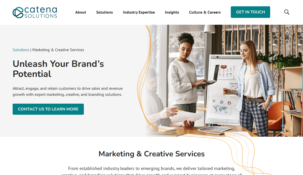 A woman presents marketing charts to a man in a modern office, with the Catena Solutions website serving as a guide for marketing, creative services, and expert website design.