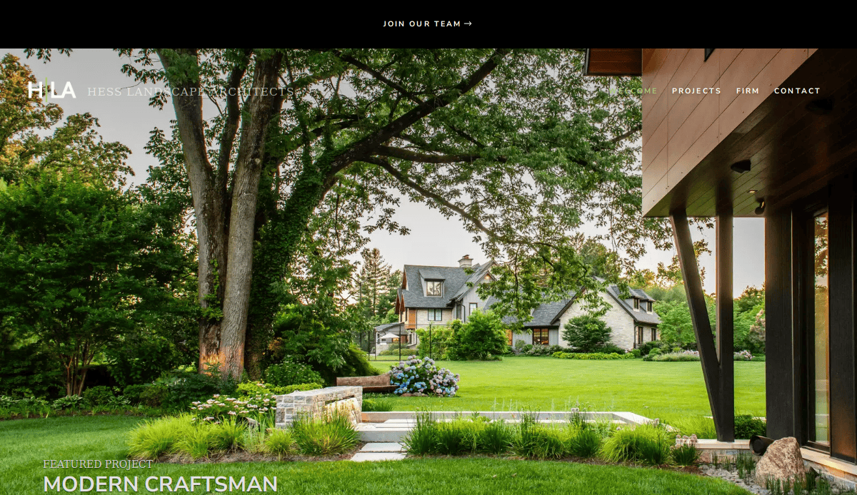 A beautifully landscaped backyard features a modern patio, green lawn, flower beds, mature trees, and a stone wall—showcasing expert landscaping services with a traditional house and lush garden in the background.