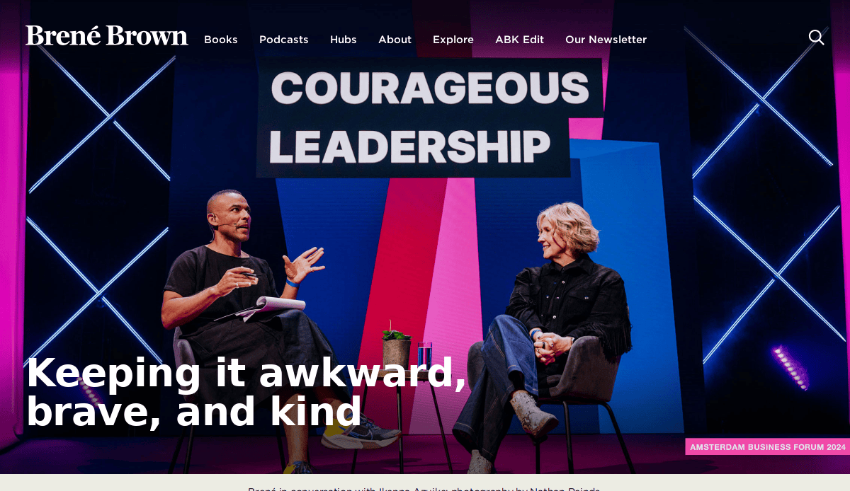Two people sit onstage beneath a COURAGEOUS LEADERSHIP sign, engaging in lively discussion. The backdrop features bold, colorful beams. Text reads, Keeping it awkward, brave, and kind—insights perfect for any life coach website looking to fix losing clients.