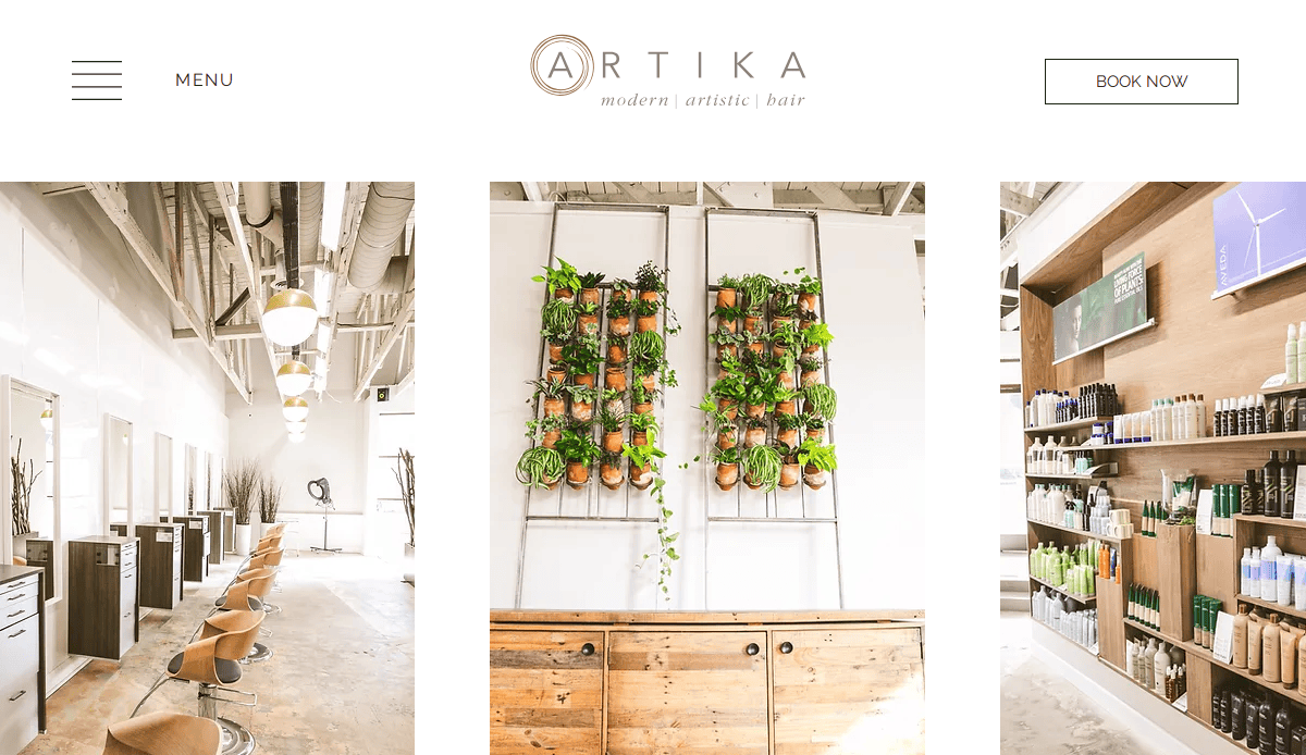 Bright, modern hair salon interior with wooden chairs and stations, a vertical wall garden with potted plants, and shelves displaying hair products. Clean, minimalist decor with natural light.
