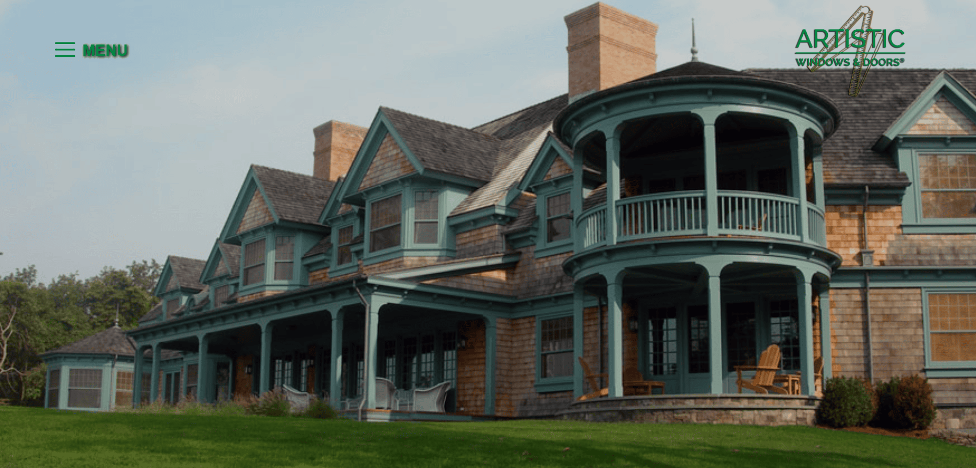A large house with natural wood siding, teal trim, wraparound porch, and upper balcony sits on a manicured lawn. The Artistic Windows & Doors logo appears in the top right corner.