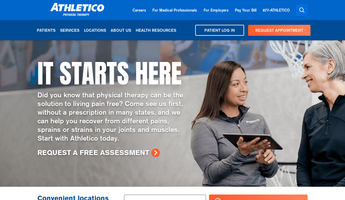 Two women talking and smiling in a physical therapy clinic. The screen displays the Athletico Physical Therapy website with text promoting physical therapy services and options to request an appointment or log in.