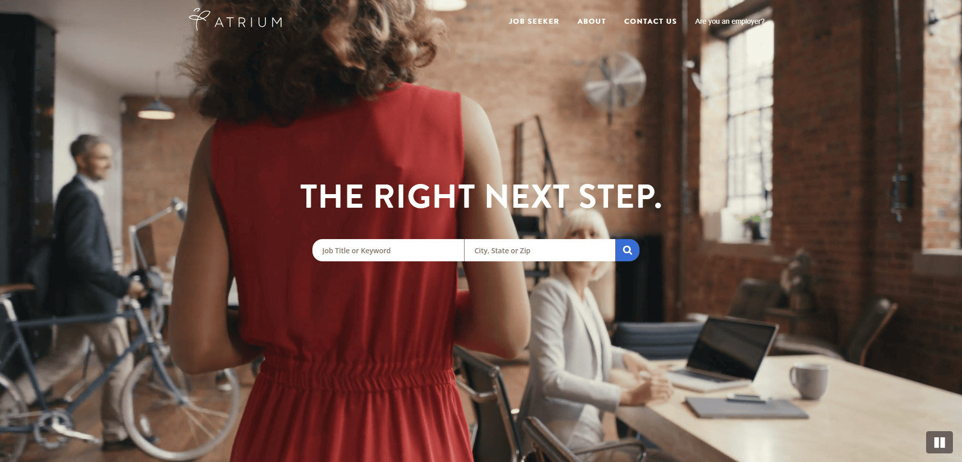 A woman in a red dress stands in a modern office with exposed brick walls, facing two seated women at a table with laptops. Text overlay reads, THE RIGHT NEXT STEP. A search bar is displayed below.