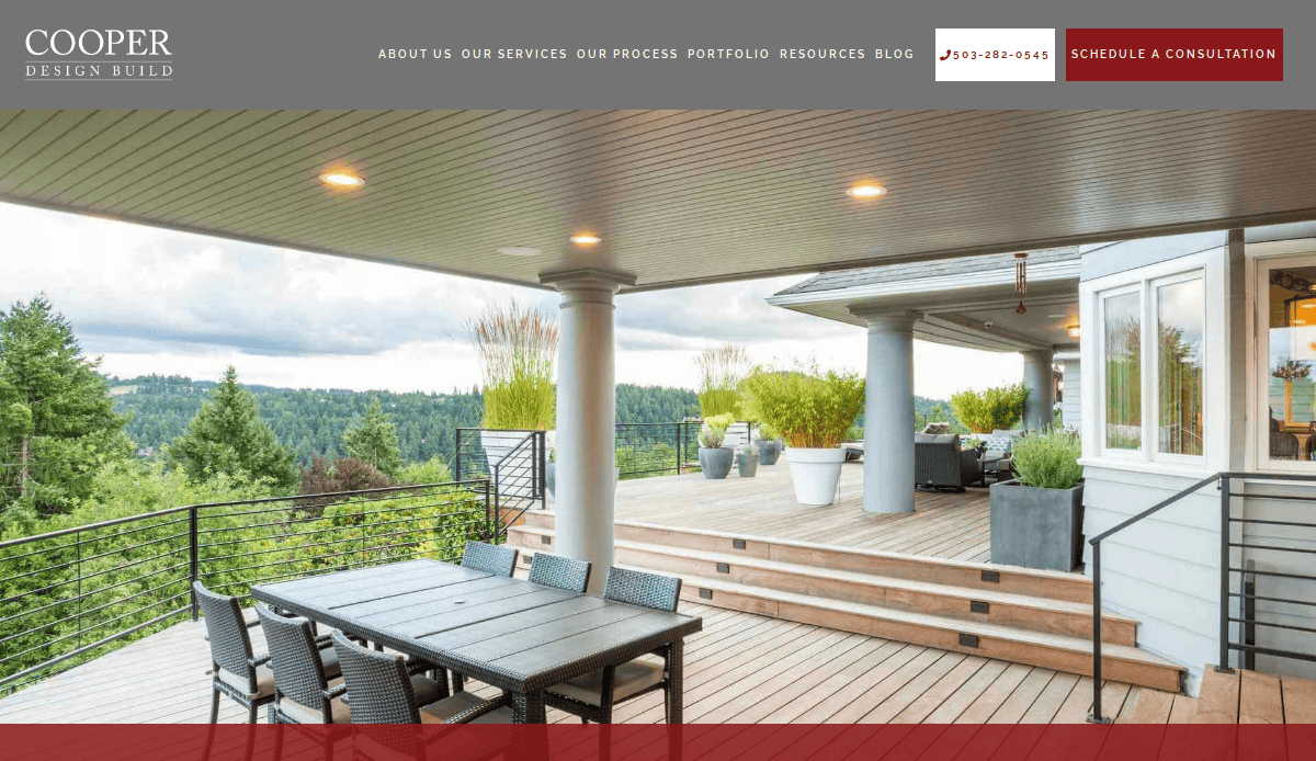 Spacious outdoor deck with seating and dining area, surrounded by trees and greenery, attached to a modern home with large windows and covered ceiling.