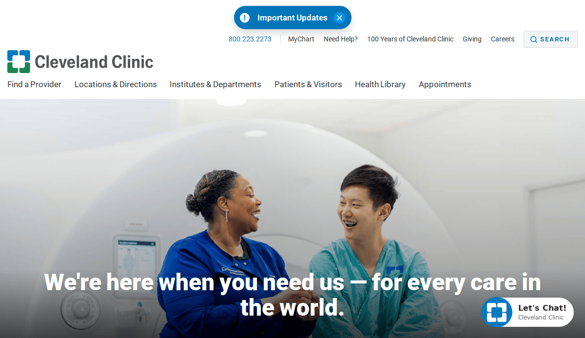 Two healthcare professionals, one in blue scrubs and the other in a white coat, sit and laugh together in a medical imaging room. The Cleveland Clinic logo and website navigation are visible above them.