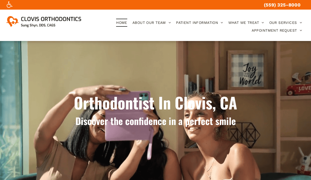 Three young women sit together and smile while taking a selfie with a pink phone. The background includes shelves with books, decor, and a framed sign that says Joy to the World. Text announces an orthodontics office in Clovis, CA.