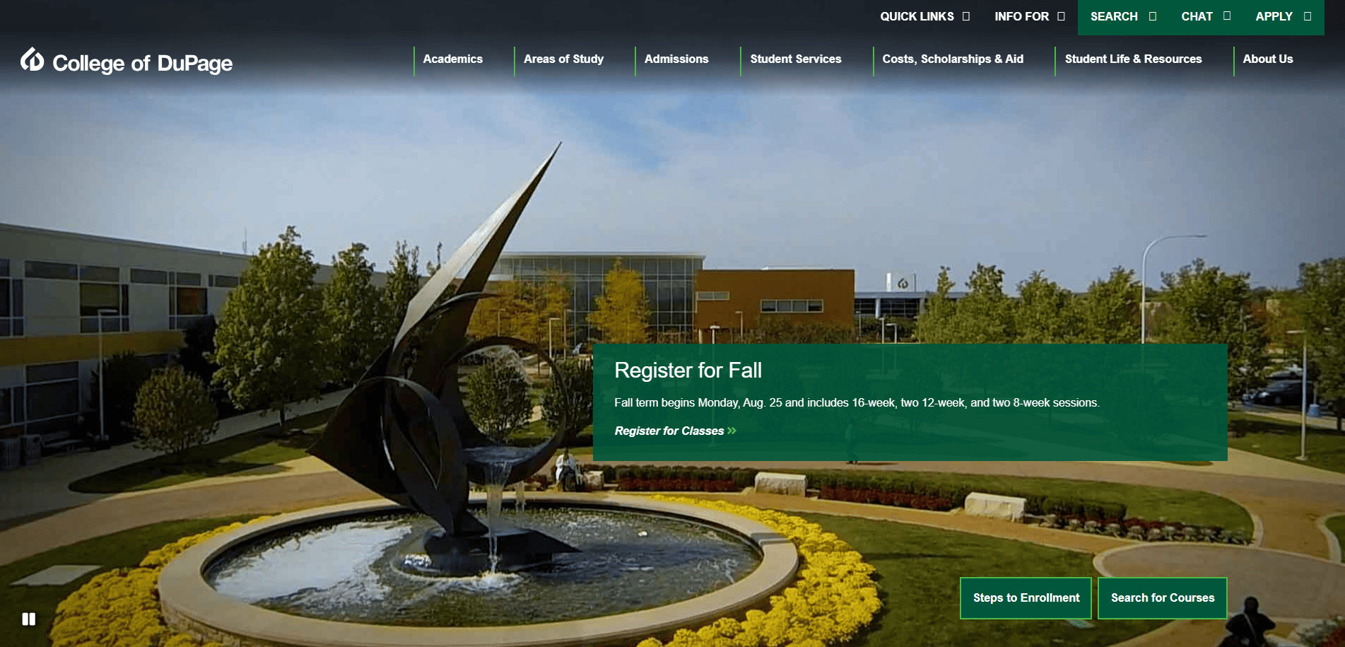 A large abstract metal sculpture rises from a circular fountain surrounded by yellow flowers on the College of DuPage campus, with modern buildings and trees in the background. A banner promotes fall registration.