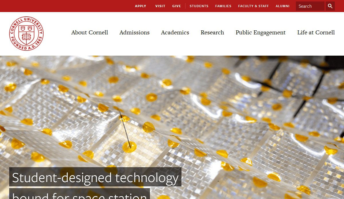 Screenshot of Cornell Universitys website featuring its logo, navigation menu, and a banner image of small, shiny, gold-accented tiles. Headline text reads: “Student-designed technology bound for space station.”.