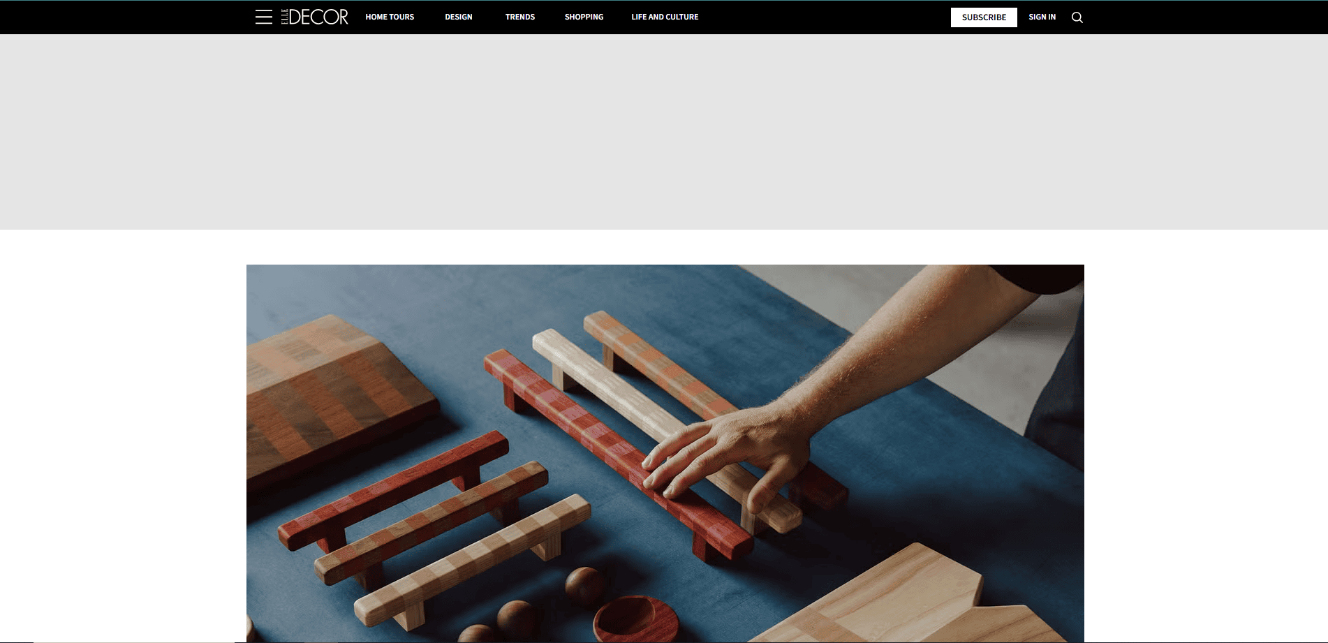 A person arranges several rectangular wooden blocks of different colors and sizes on a blue surface, with additional wooden items nearby.
