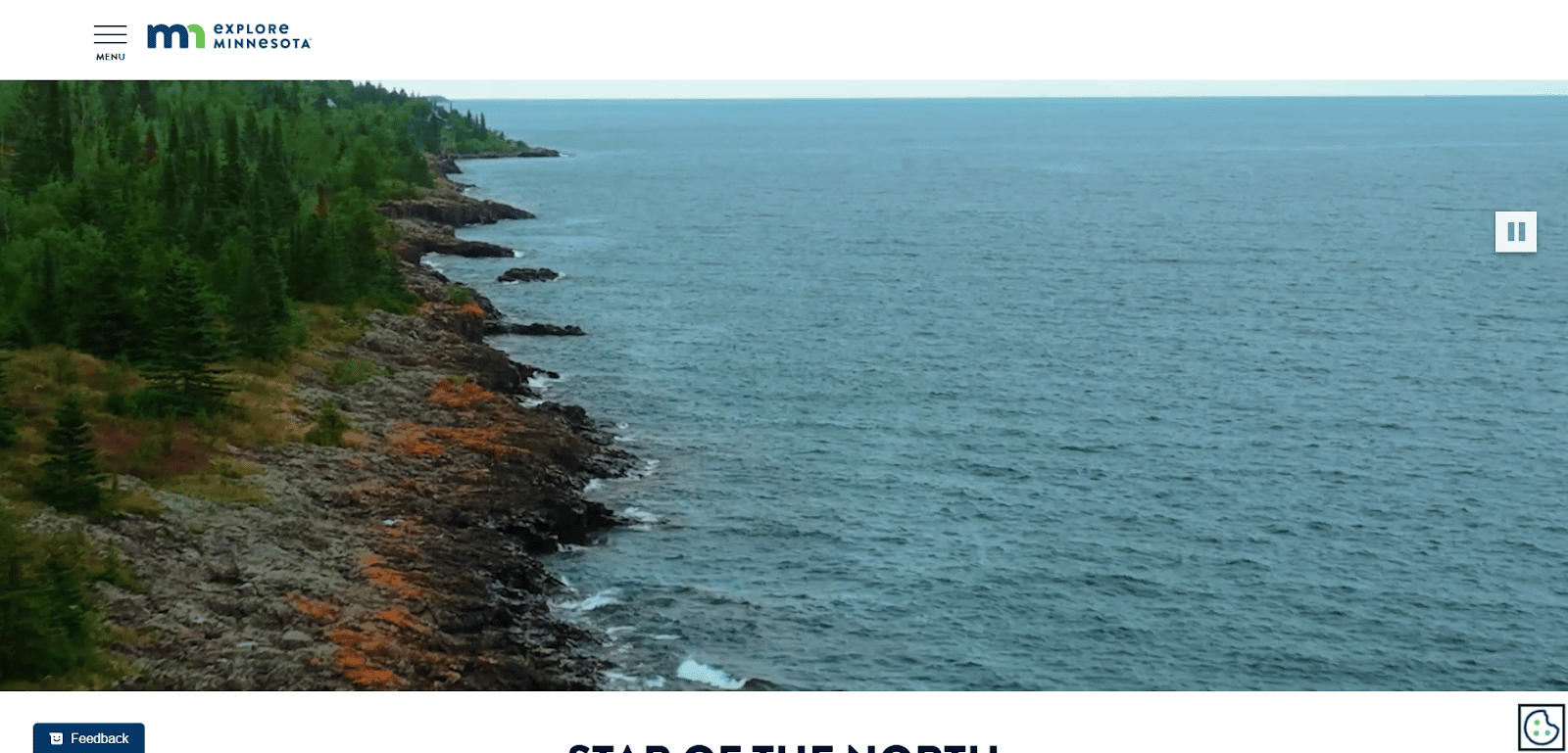 A rocky shoreline with green trees meets the blue waters of a large lake under a cloudy sky. The image is part of the Explore Minnesota website.