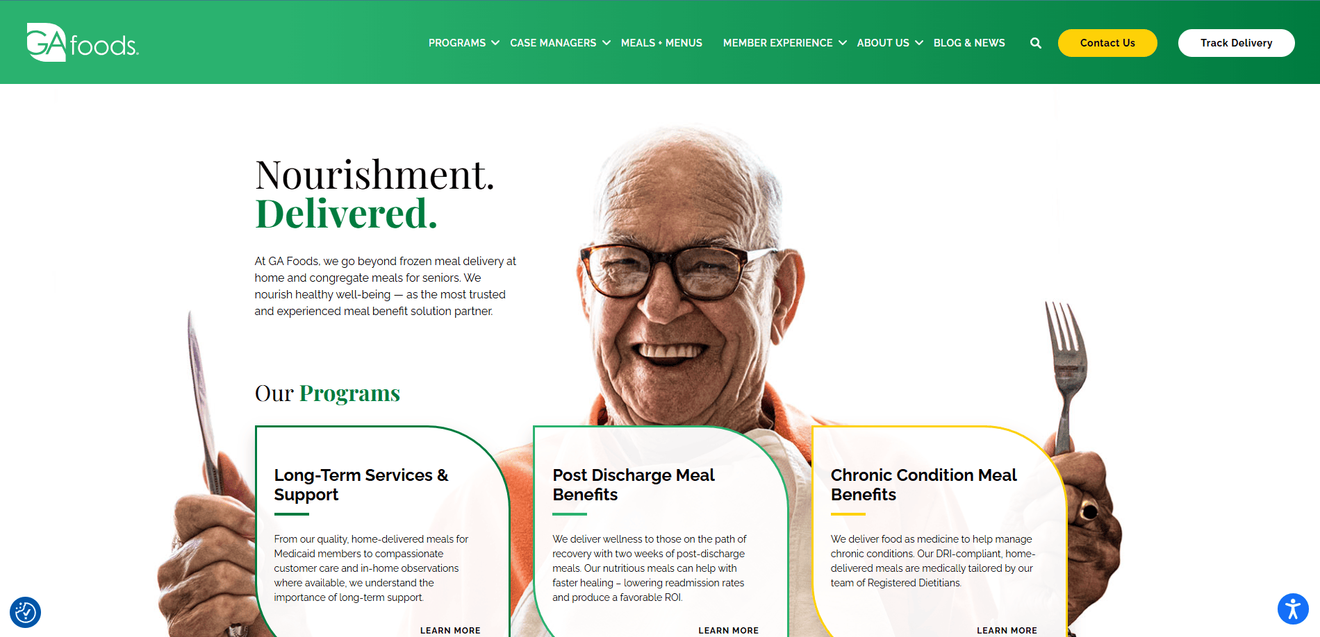 A smiling elderly man wearing glasses holds a fork with food. The website promotes GA Foods’ meal delivery services, featuring sections on long-term services, post-discharge meals, and chronic condition meal benefits.