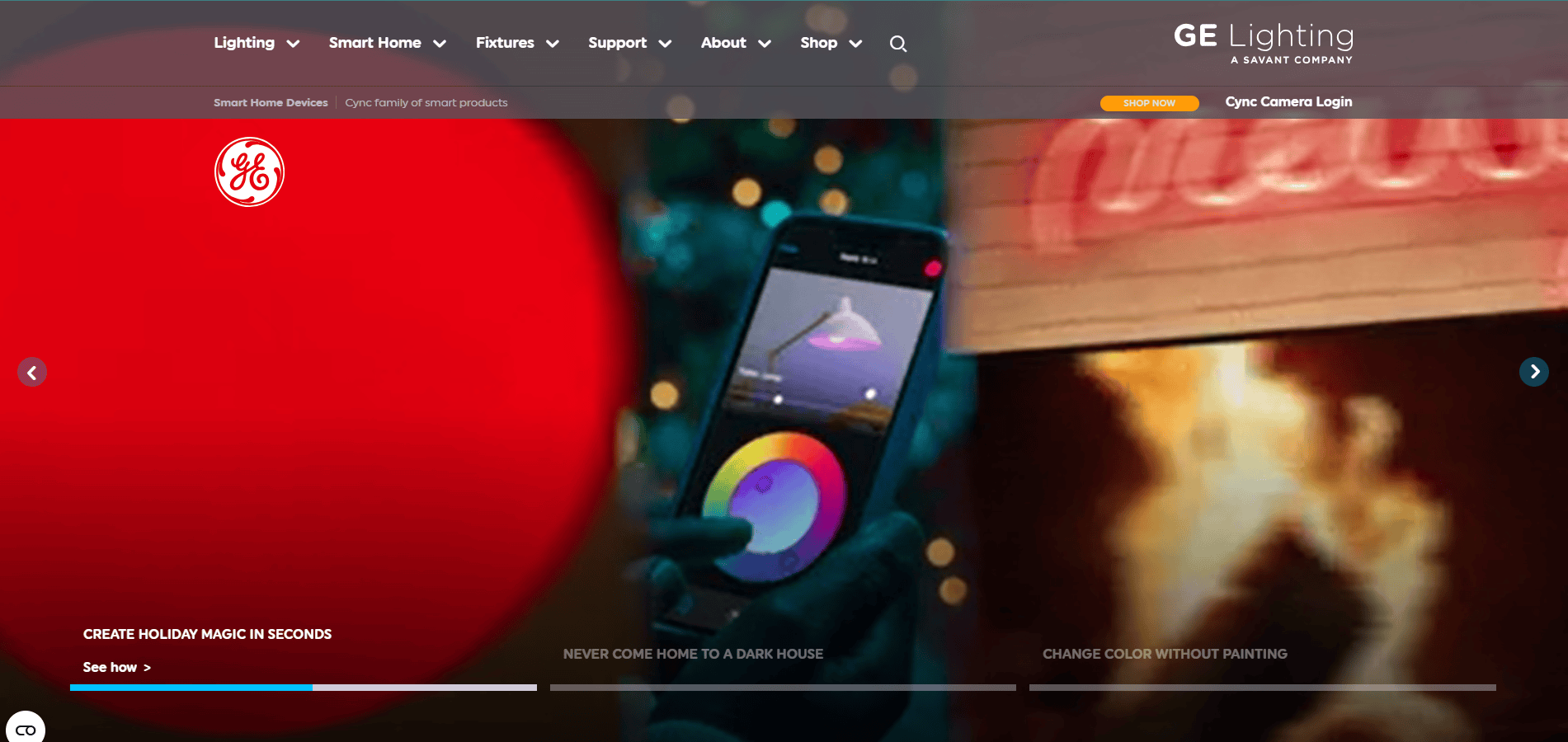 A website homepage for GE Lighting features a navigation bar, a bright red GE logo, a hand holding a smartphone with a colorful app, and blurred holiday lights, promoting smart home lighting controls.