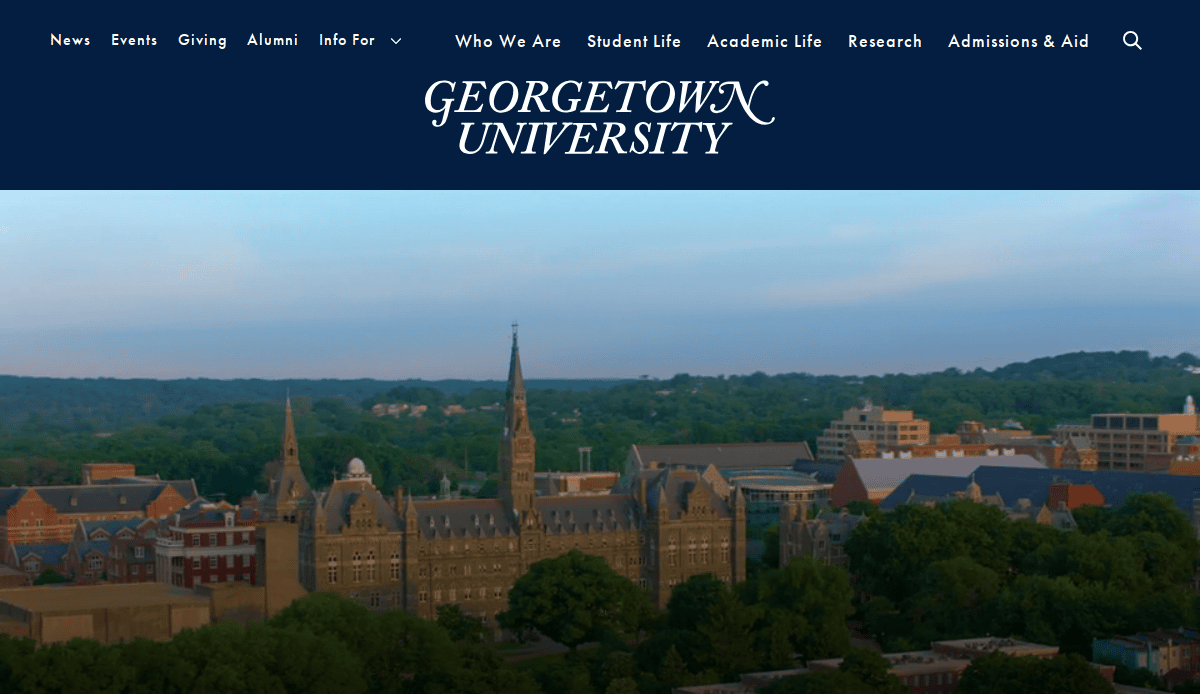 Aerial view of Georgetown University’s campus with Healy Hall in the foreground, surrounded by trees and buildings, beneath a blue banner displaying the university’s name and website navigation links.