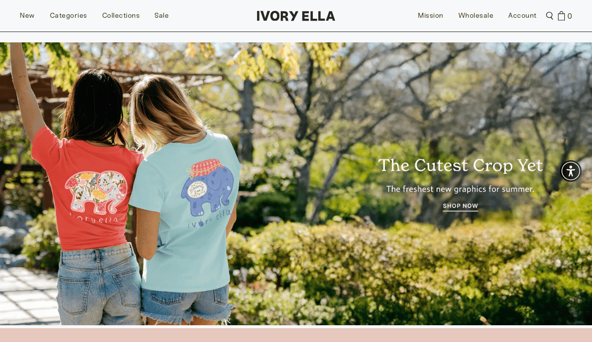 Two women stand outdoors with their backs to the camera, wearing colorful Ivory Ella t-shirts featuring large elephant graphics. Text reads, The Cutest Crop Yet. The freshest new graphics for summer. SHOP NOW.