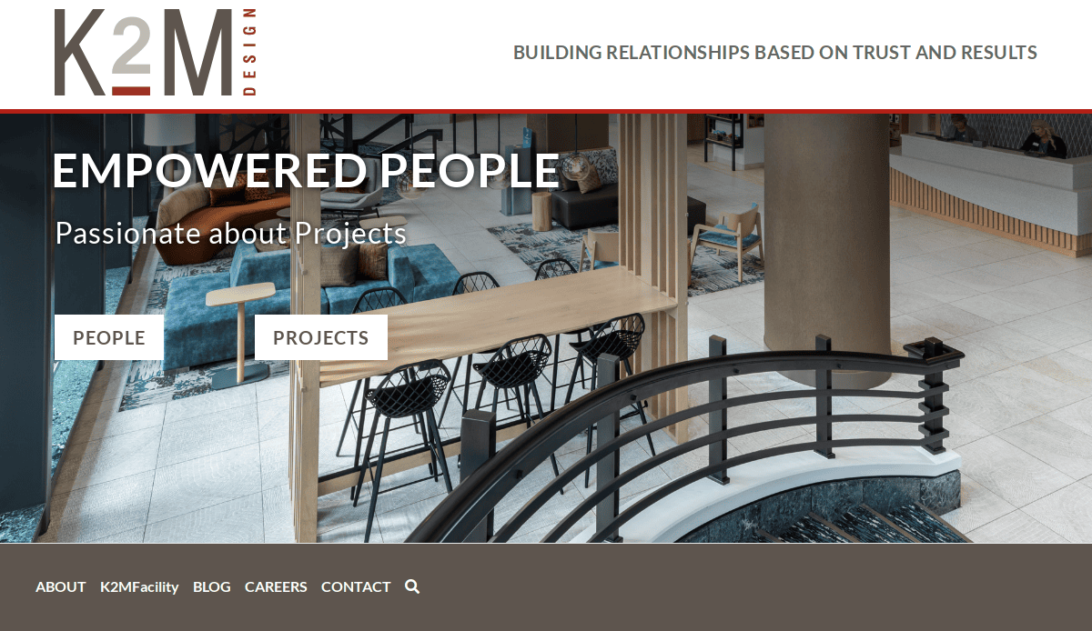 A modern office lobby with stylish seating, wood and metal accents, and a curved black railing, overlaid with the K2M Design logo and navigation options for people, projects, and company information.