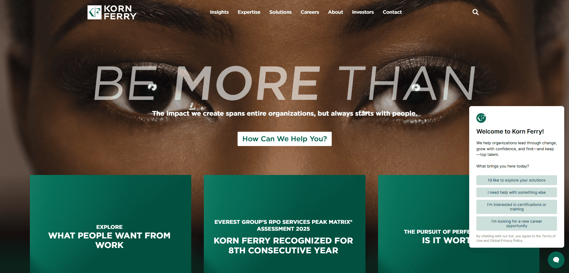 Screenshot of the Korn Ferry website homepage, featuring a close-up of a person’s eyes, the phrase “BE MORE THAN,” and navigation menus. A chatbot window appears on the right, offering help.