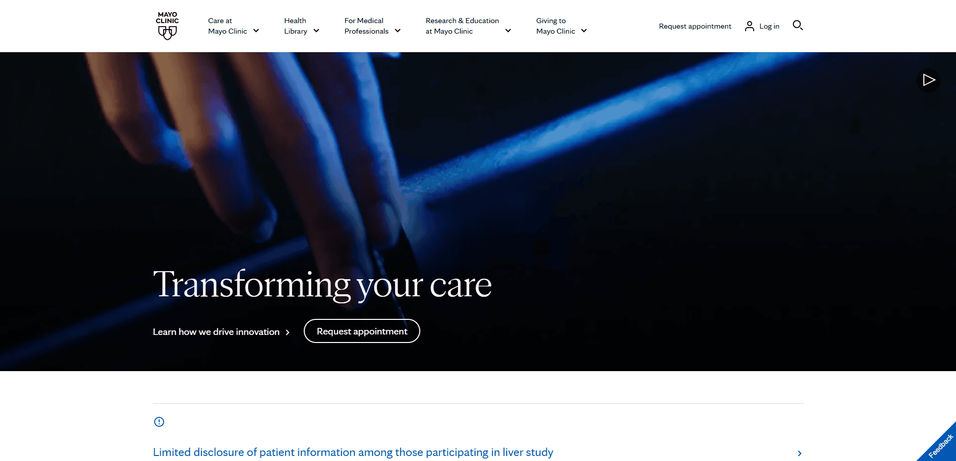 A close-up of a hand touching a surface with a blue glow, overlaid with the text Transforming your care and buttons labeled Learn how we drive innovation and Request appointment.