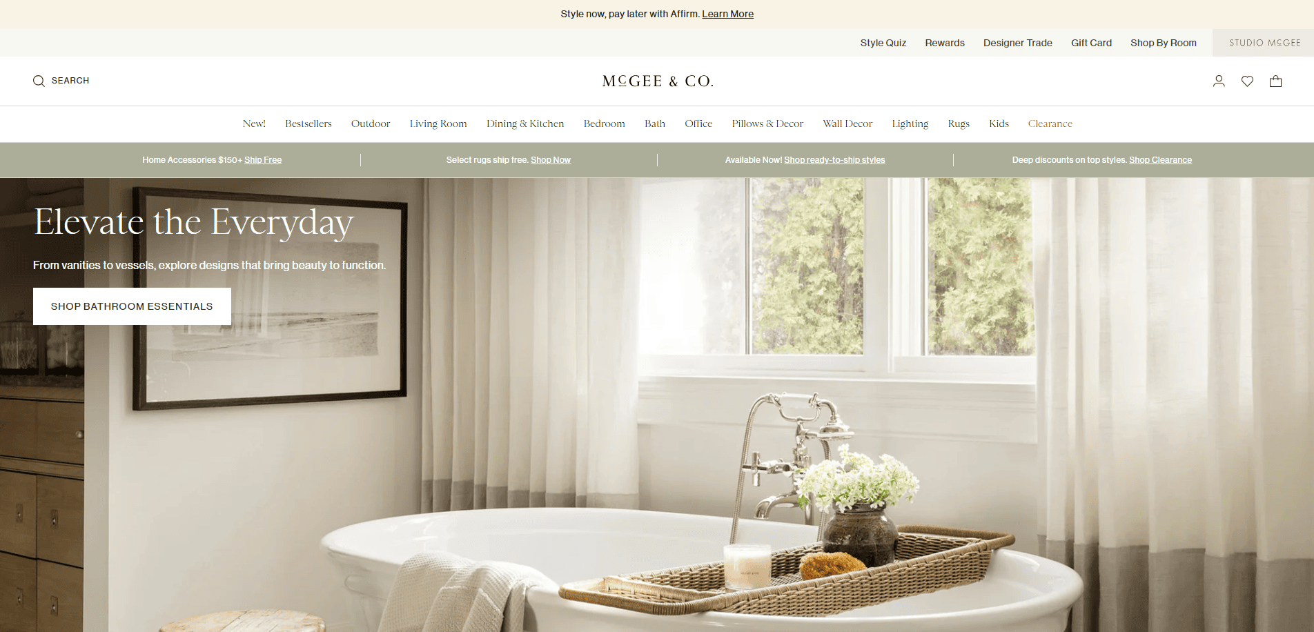 Bathroom with a white freestanding tub, tray holding towels and a vase, and large windows with sheer curtains letting in natural light. The scene feels calm, elegant, and inviting.