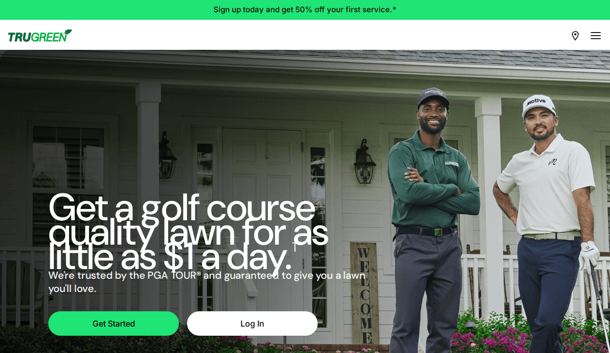 Two men in golf attire stand smiling in front of a house with a welcome sign. The text promotes TruGreen lawn care services, offering golf course quality lawns for as little as $1 a day. Green buttons read Get Started and Log In on the lawn care website.