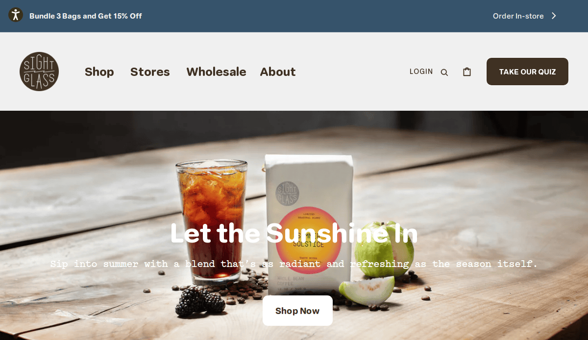 Homepage of Sightglass Coffee’s website showing a cold brew drink, a bag of coffee beans, a sliced lime, and a leafy branch on a table, with the text “Let the Sunshine In” and a “Shop Now” button.