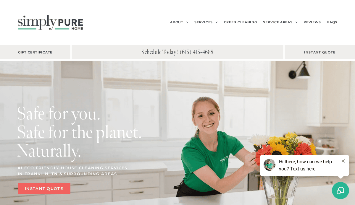 A woman in a green shirt arranges a colorful bouquet of flowers in a bright, modern kitchen. Text on the image promotes eco-friendly home cleaning services. A chat box appears in the lower right corner.