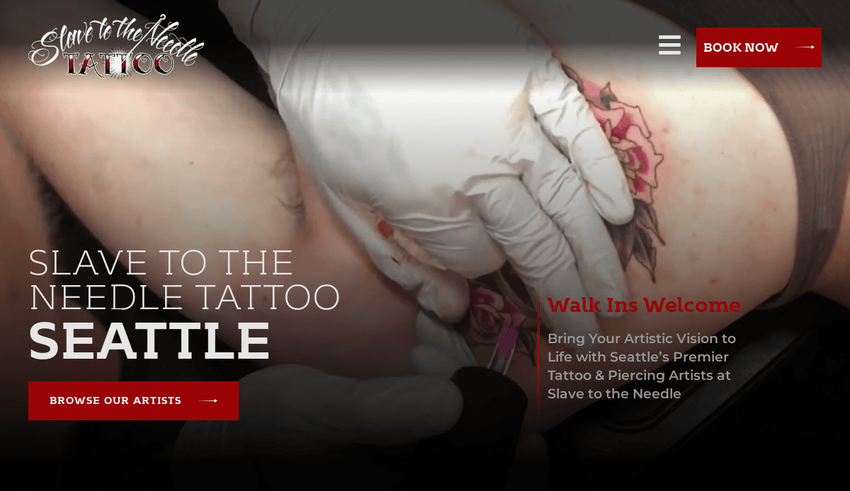 A tattoo artist wearing white gloves works on a clients leg, creating a colorful tattoo. The text advertises Slave to the Needle Tattoo in Seattle, inviting walk-ins and bookings, with options to browse artists.