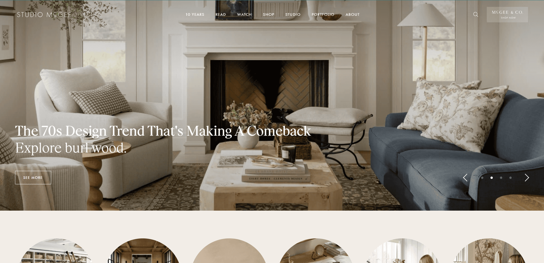 A living room with neutral tones, a white fireplace, beige armchair, blue sofa, wooden coffee table, and decorative accents. Text overlay reads: The 70s Design Trend Thats Making A Comeback. Explore burl wood.