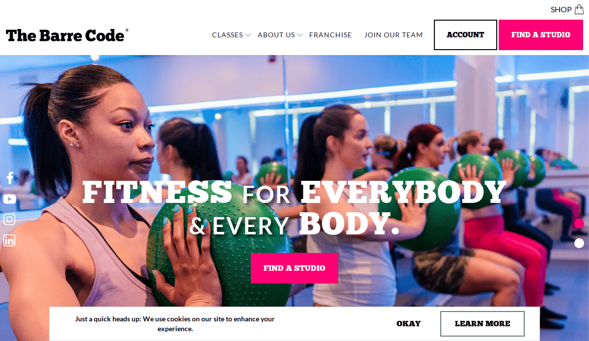 A diverse group of women in workout attire exercise with green weighted balls in a brightly lit fitness studio. The text overlay promotes The Barre Code and invites users to find a studio.