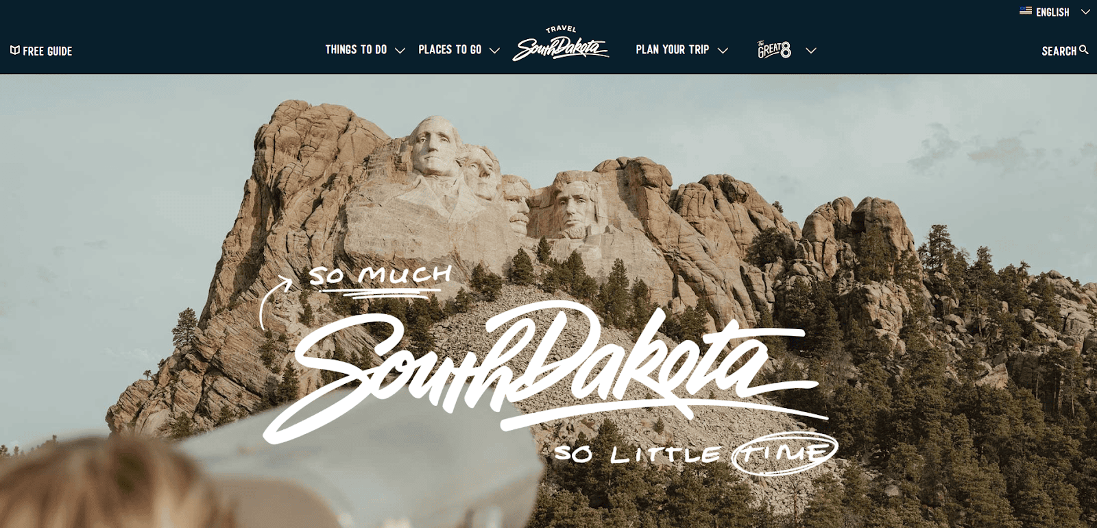 Mount Rushmore with four presidential faces carved in stone, trees below, and a telescope in the foreground. Bold text reads: So much South Dakota, so little time.