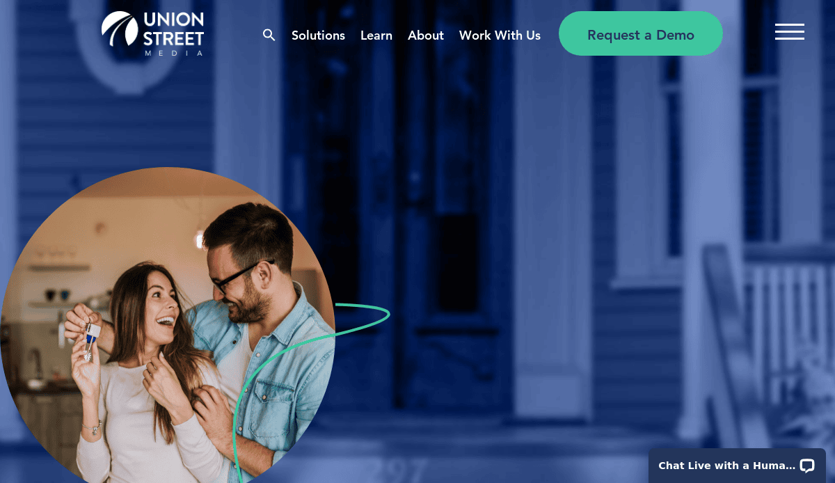 A happy couple stands in a kitchen, smiling and holding a set of house keys. The Union Street Media website is overlaid, with navigation and a Request a Demo button visible at the top.