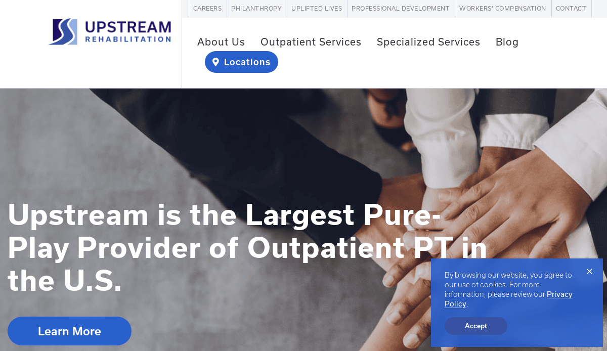A website homepage for Upstream Rehabilitation, featuring a banner with hands stacked together and text stating, Upstream is the Largest Pure-Play Provider of Outpatient PT in the U.S. A cookie consent pop-up appears at the bottom right.