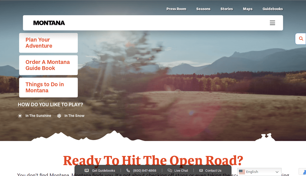 Website homepage for Montana tourism, featuring a scenic blurred photo of a road with trees and mountains in the background. Menu options include planning adventures, ordering a guidebook, and exploring activities.