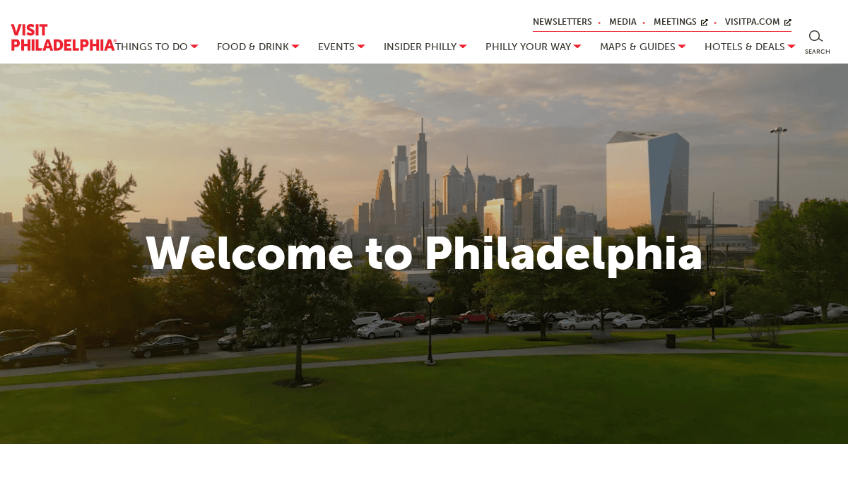 A city park with green grass and scattered trees in the foreground, and Philadelphia’s skyline with modern skyscrapers under a cloudy sky at sunset. Text reads, Welcome to Philadelphia.