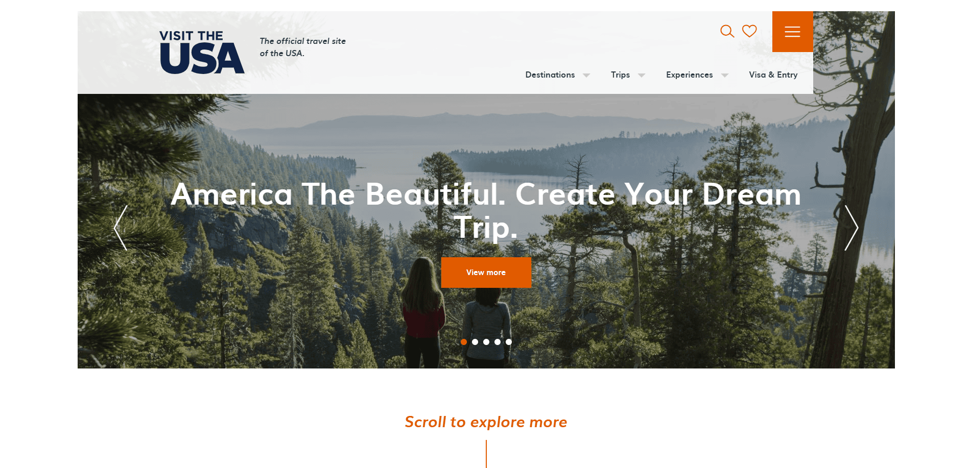 Two people stand on a forested overlook with a lake and mountains in the distance. The website banner reads, America The Beautiful. Create Your Dream Trip. The page header says Visit The USA.