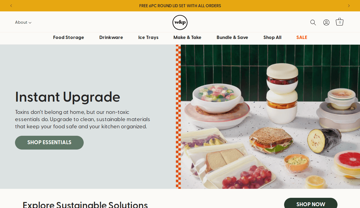 A variety of reusable food containers filled with sandwiches, fruit, and snacks are displayed on a marble countertop next to a dark green tiled wall, promoting sustainable kitchen storage solutions.